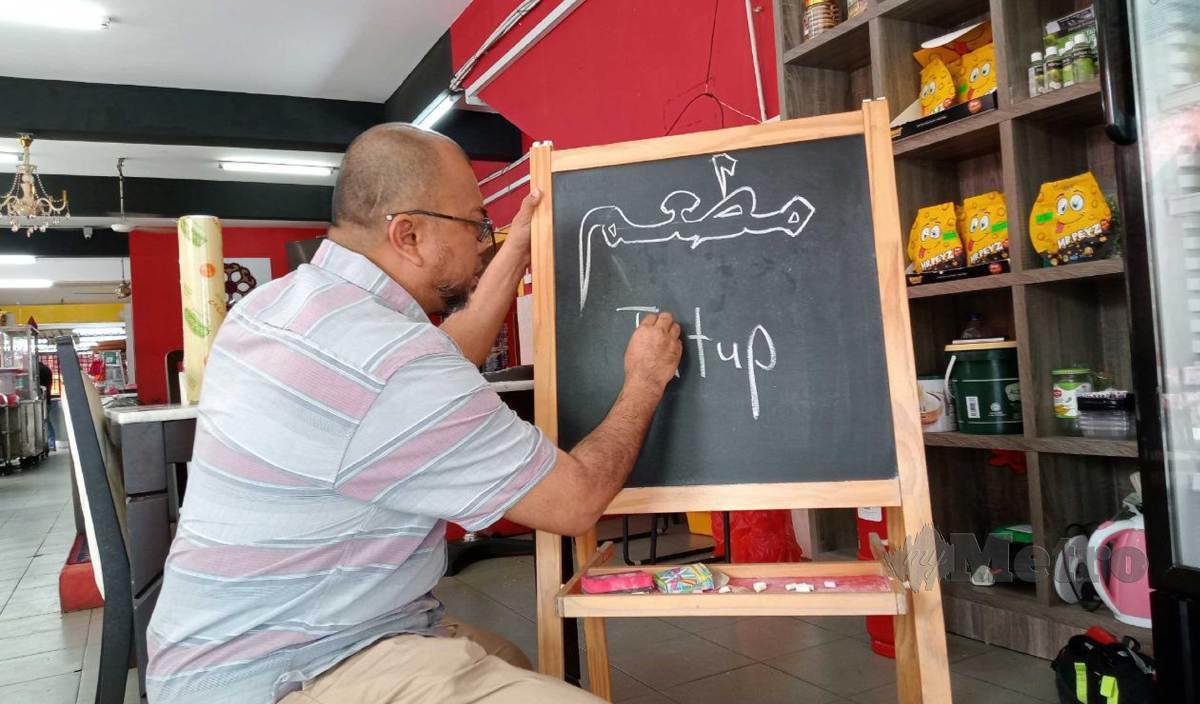 ZULRAHIM menulis notis pemberitahuan yang menyatakan restorannya ditutup akibat ketiadaan air. FOTO Omar Ahmad