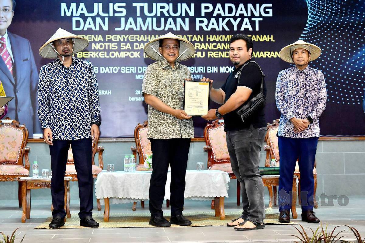 AHMAD Samsuri (tengah) menyampaikan surat hak milik tanah RTB DUN Rhu Rendang di Dewan Majlis Daerah Marang. FOTO Ghazali Kori