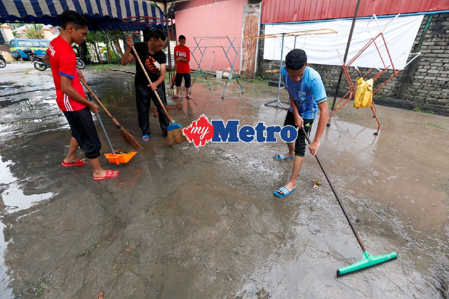 Penduduk membersihkan kawasan kediaman masing-masing selepas banjir surut di Jalan P Ramlee, Georgetown. - Foto RAMDZAN MASIAM 