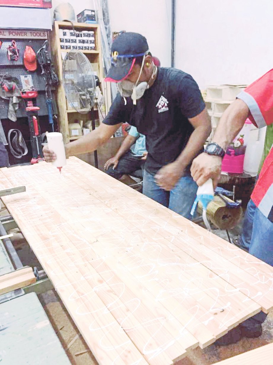 PROSES melicinkan permukaan kayu untuk menyiapkan rehal al-Quran.