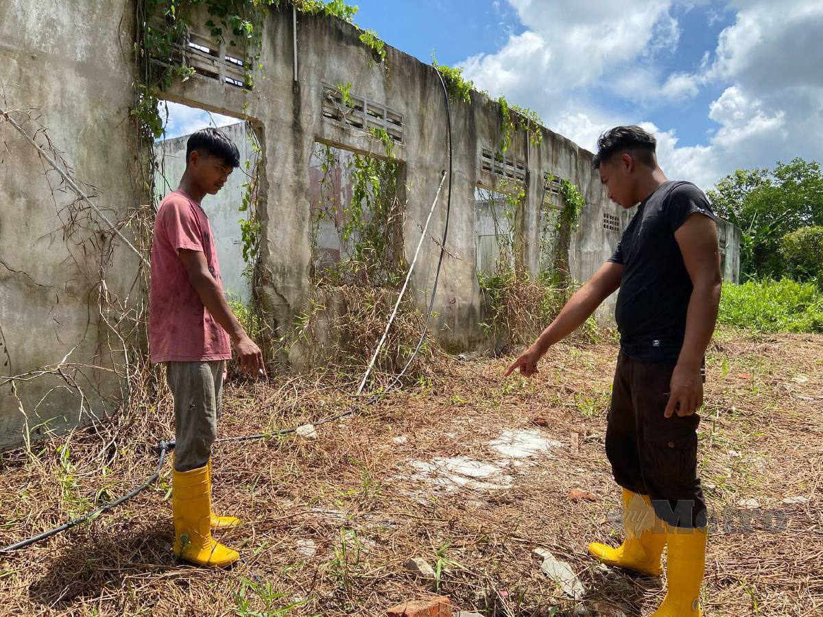 MOHAMMAD Daniel (baju hitam) dan Mohd Syazrul Danish menunjukkan lokasi penemuan tulang manusia di Kampung Batu 7, Tongkang Pechah. FOTO Alias Abd Rani