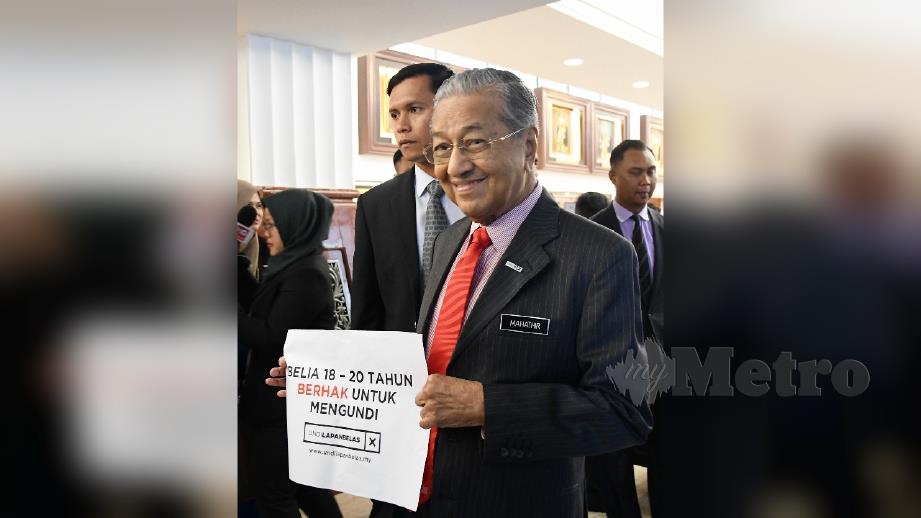 Dr Mahathir memegang poster menyokong rang undang-undang pindahan had umur 18 tahun untuk layak mengundi di Bangunan Parlimen. FOTO Mohamad Shahril Badri Saali