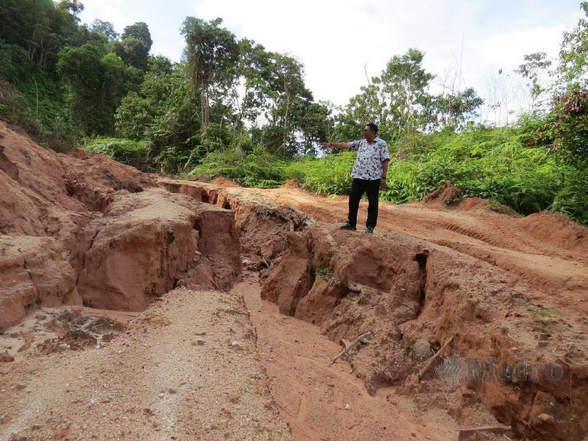 Mohd Syahbuddin menunjukkan jalan rosak dan pernah berlaku tanah runtuh di laluan menuju ke Pos Balar, di sini. FOTO Paya Linda Yahya