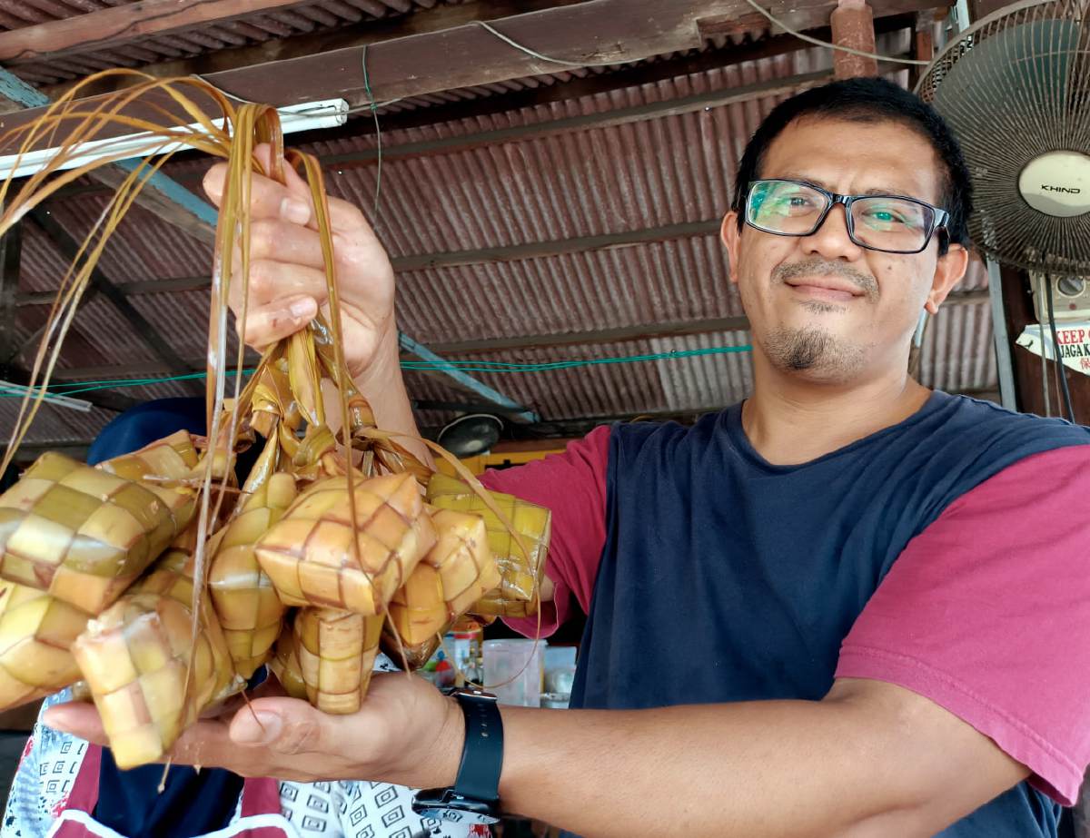 MOHAMAD Zaim menunjukkan ketupat nasi yang siap direbus dijual di kedainya di Kampung Bukit Godek, Semabok, Melaka. FOTO BERNAMA
