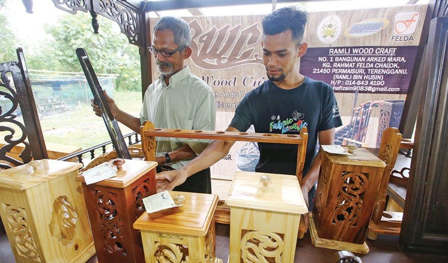 RAMLI (kiri) dan Mohd Amirul bersama produk kraf kayu dihasilkan RWC untuk pasaran tempatan.