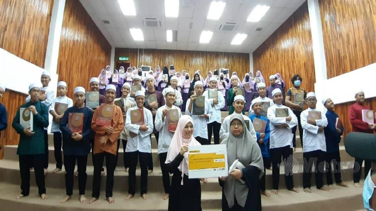 DR AZURAIDA (kiri) menyerahkan sumbangan kepada wakil tahfiz disaksikan pelajar yang menerima al-Quran ketika program berkenaan. FOTO ihsan pembaca