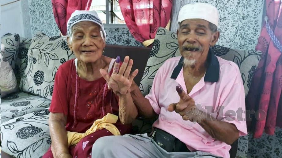SALLEH Dahlan (kanan) dan isteri, Jenab Jaman, menunjukkan jari yang dicelup dakwat bukti sudah menunaikan tanggungjawab mengundi pada PRK Parlimen Tanjung Piai, Pontian. FOTO Mohd Fahmi Yusof