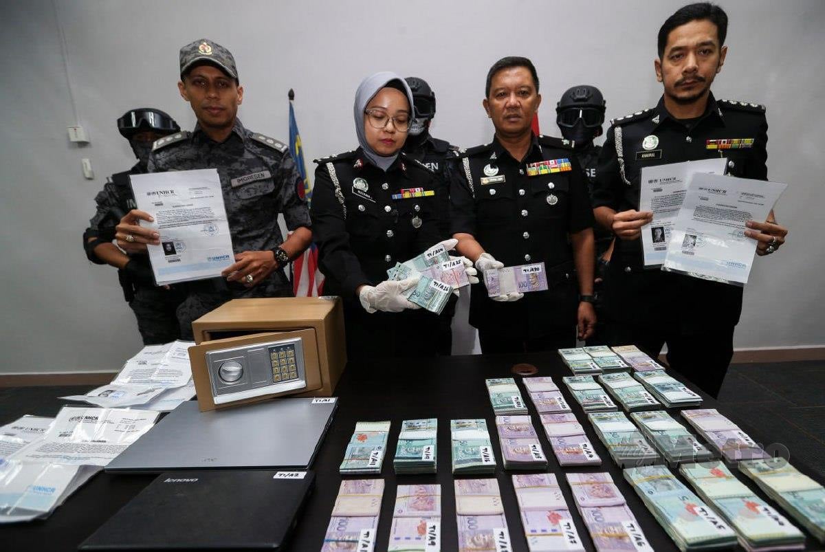 RUZAANA (tengah) bersama pegawainya menunjukkan rampasan wang tunai RM140,000 daripada sindiket pemalsuan slip permohonan kad UNHCR pada sidang media di Kompleks Imigresen Negeri Kelantan. FOTO Nik Abdullah Nik Omar