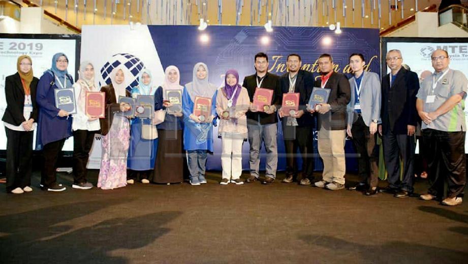 DR Khamsa Suryati (tujuh dari kanan) menunjukkan anugerah khas 'The Best Award' bersama pensyarah lain selepas berjaya meraih enam pingat dalam MTE 2019 di PWTC. FOTO ihsan UniSZA.
