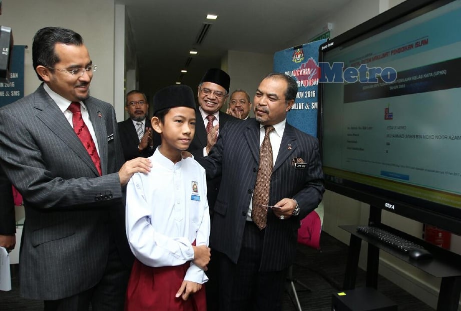 Jamil Khir bersama murid cemerlang UPKK, Muhammad Uwais Mohd Nor Azam yang mendapat 8A ketika melancarkan semakan keputusan UPKK 2016 di Kompleks Islam Putrajaya, hari ini. - Foto AHMAD IRHAM MOHD NOOR