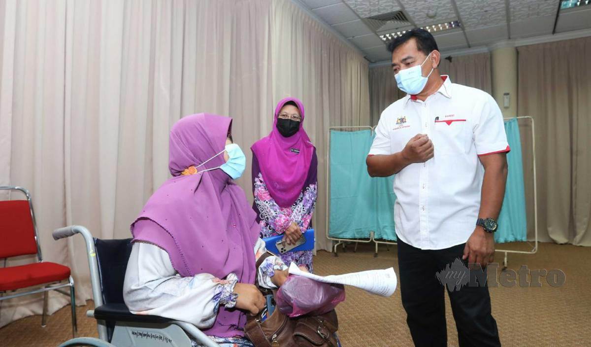RAHMAD (kanan) bersama Pengarah Hospital Melaka Dr Zaharimah (tengah) berbual dengan warga emas yang menerima suntikan vaksin ketika melawat Special PPV yang bertempat di Masjid Al-Azim. FOTO Syafeeq Ahmad