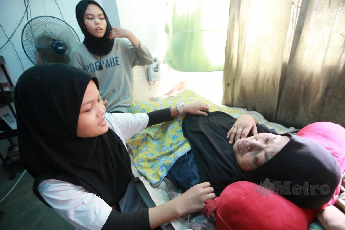 Nur Imman (tengah) menguruskan ibunya Norizan yang terlantar sakit manakala Nur Hidayah turut menjaga ketika di temui di rumahnya di PPR Setapak Indah. FOTO FATHIL ASRI