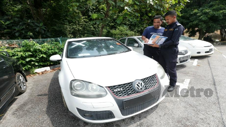 Anggota JPJ Mohd Iskandar Abd Taib (kanan) dan Muhammad Akmal Ibrahim (kiri) melihat Volkswagen Golf GTI 2.0 yang dibida pada harga RM30,100 di Program Lelongan Awam Kenderaan Sita di JPJ Melaka di Bukit Katil hari ini. Foto Khairunisah Lokman