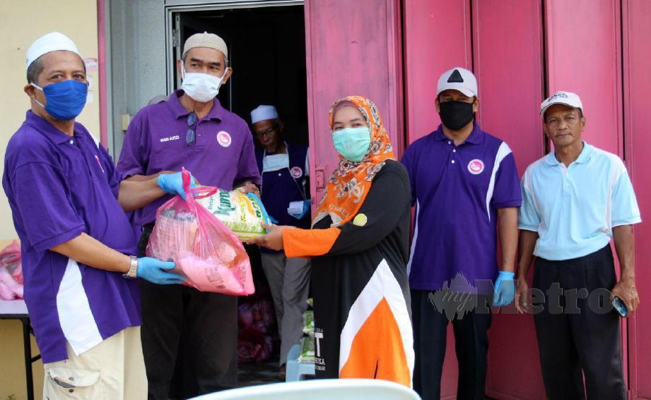 WAKIL KBJIKN menyerahkan sumbangan barangan dapur kepada penerima yang terjejas. FOTO  Nik Abdullah Nik Omar