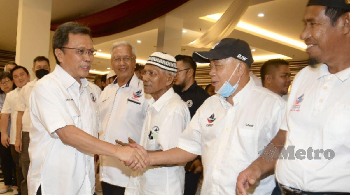 MOHD Shafie (kiri) bersalaman dengan Ketua Bahagian Tanjung Aru, Osman Rais (dua kanan) ketika hadir pada Program Bersama Akar Umbi Putatan. FOTO Mohd Adam Arinin.