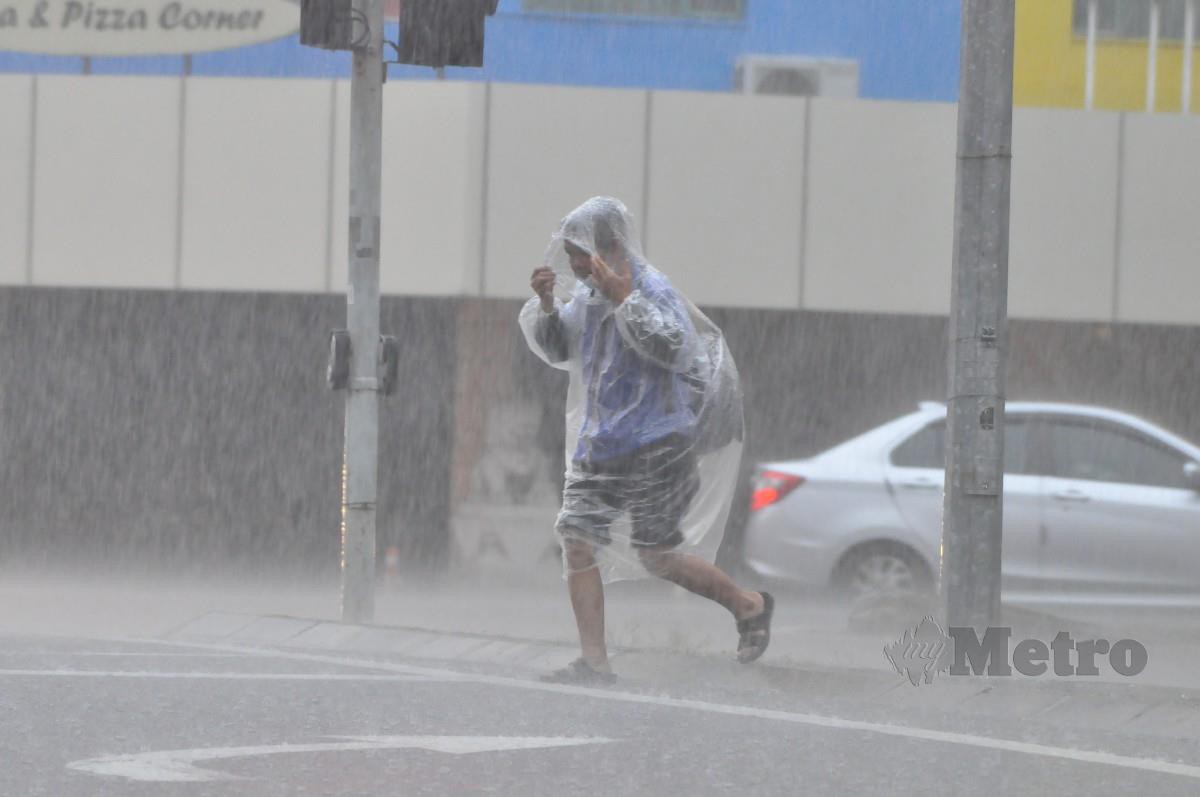 Seorang individu berbaju hujan melintas jalan ketika hujan lebat yang berterusan sejak tengah malam tadi. MetMalaysia mengeluarkan amaran hujan yang dijangka berterusan di beberapa tempat di Pantai Barat Sabah pagi ini. FOTO MOHD ADAM ARININ