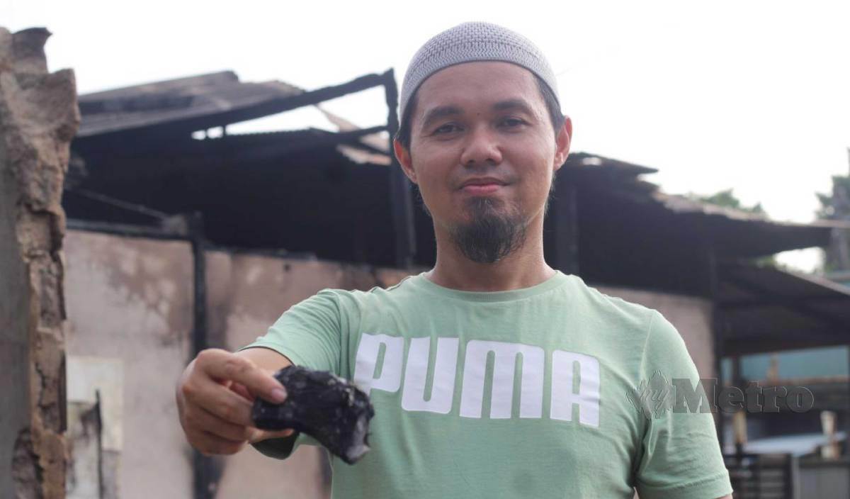 WAN Mohd Shahrul menunjukkan wang tunai yang hangus dalam kejadian kebakaran di kedai runcit milik keluarganya di Kampung Gaal, Pasir Puteh. FOTO Nor Amalina Alias. 