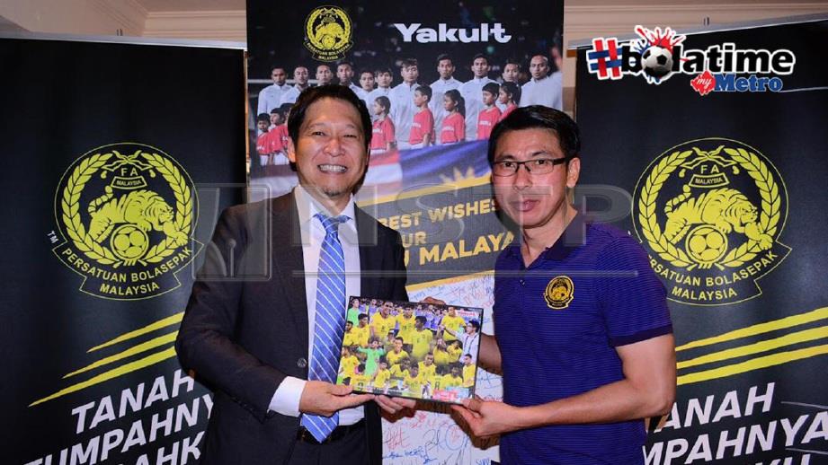 Pengarah Urusan Yakult (M) Sdn Bhd, Hiroshi Hamada menyerahkan bingkai gambar aksi Piala AFF 2018 beserta kad ucapan selamat maju jaya kepada Cheng Hoe. FOTO Ihsan Sportflex Malaysia