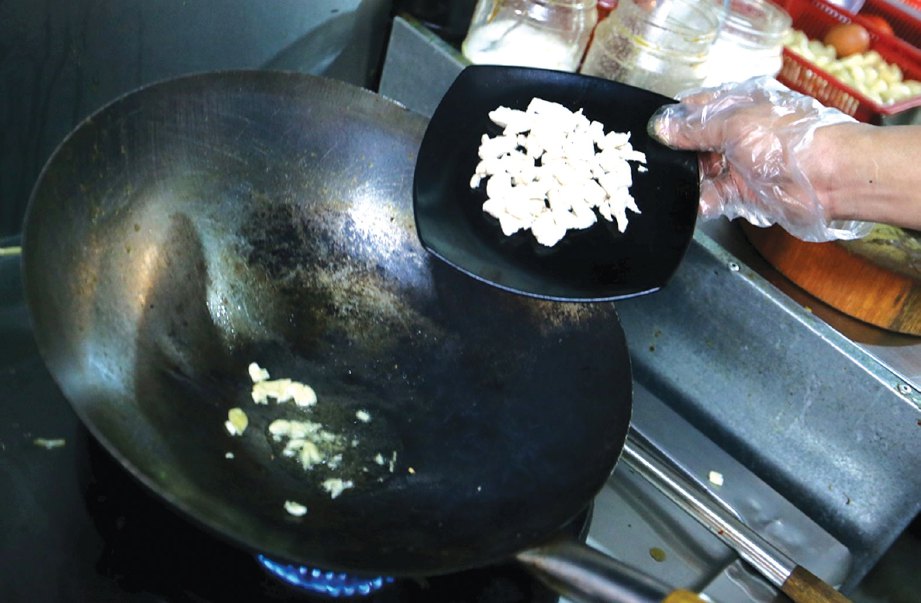 5. DALAM kuali sama, panaskan minyak dan tumis bawang putih sebelum masukkan ayam yang sudah direbus.