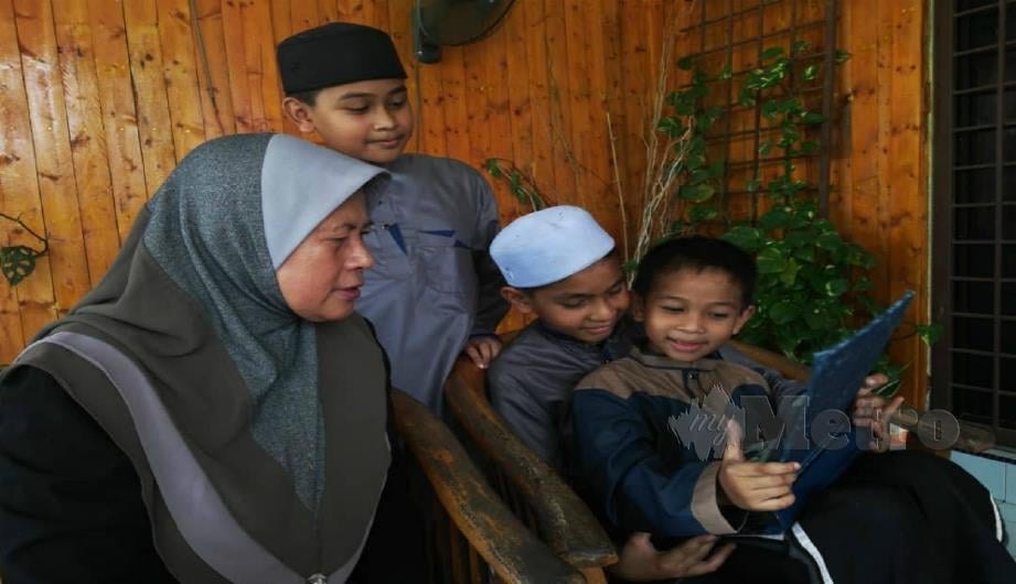 Muhammad Daris Wafiy bersama dua adiknya, Muhammad Daris Rayyan dan Muhammad Daris Amsyar bersama nenek, Fatimah Bujang, 61, melihat album kenangan keluarga mereka. FOTO Noor Hidayah Tanzizi.