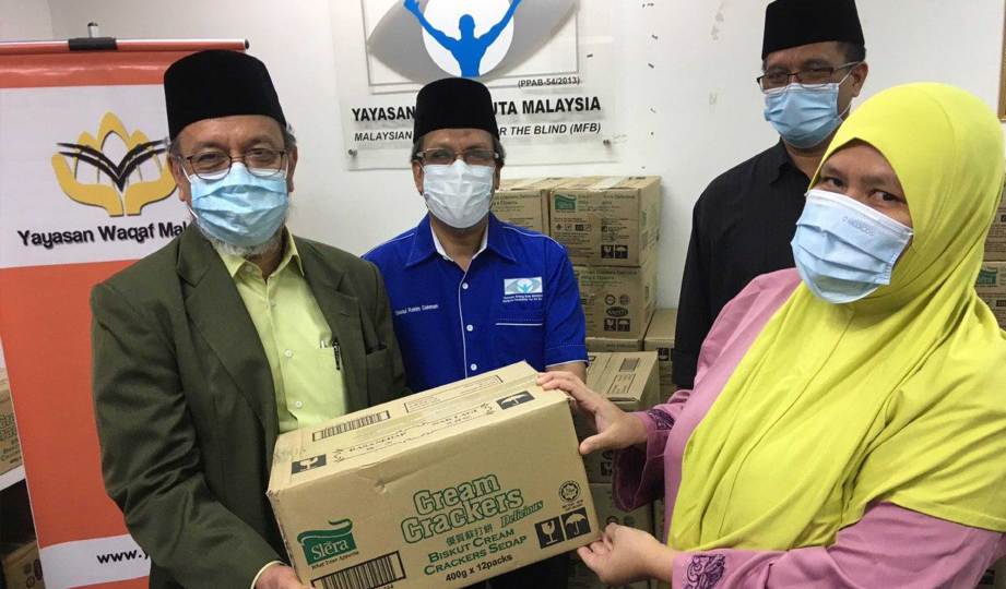 WAN Mohamad (kiri) menyerahkan sumbangan kepada ahli Yayasan Orang Buta Malaysia (YOBM) sambil disaksikan Ketua Pegawai Eksekutif YOBM, Silatul Rahim Dahman (dua dari kiri).