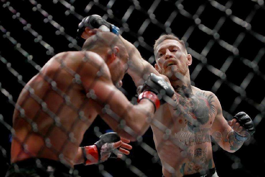 Conor McGregor (kanan) melakukan tumbukan ke arah Eddie Alvarez dalam pertarungan UFC. FOTO File AFP