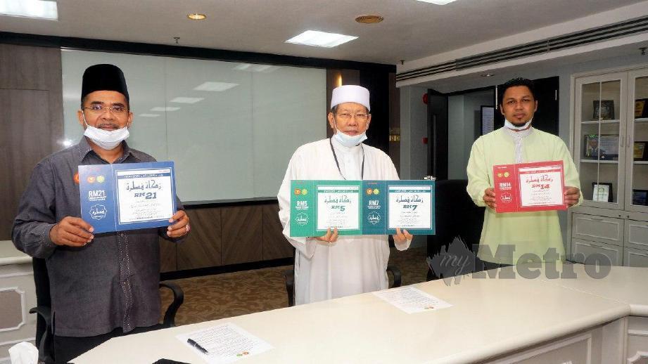 SYEIKH Fadzil Awang (tengah) dan Syeikh Zakaria (kiri) menunjukkan kadar zakat fitrah baharu iaitu RM5,RM7,RM14 dan RM21. FOTO Noorazura Abdul Rahman