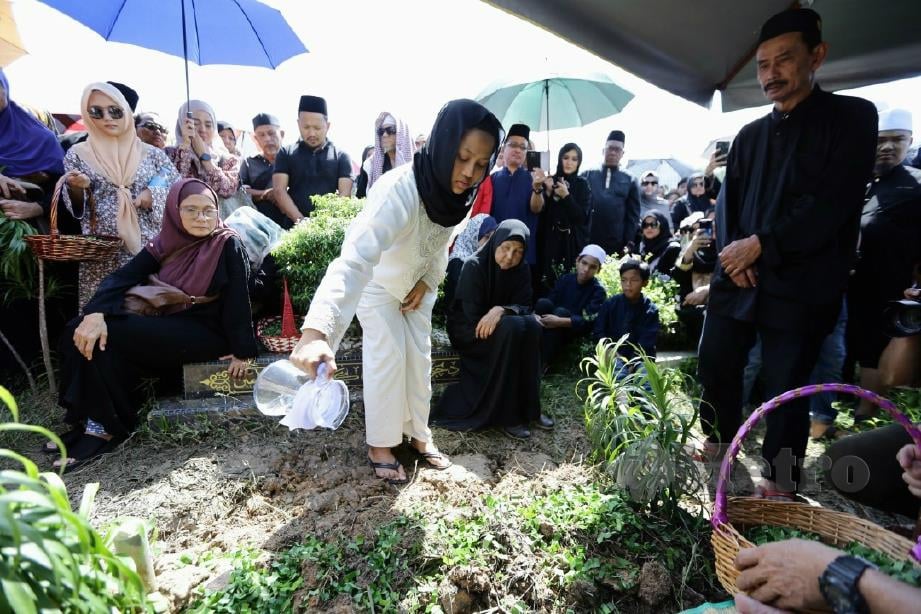 ANAK Allahyarham Datuk Nassier Wahab, 57, Intan Najihah menyiram air pada pusara bapanya di Tanah Perkuburan Islam Bukit Batu Belah. FOTO Roslin Mat Tahir.